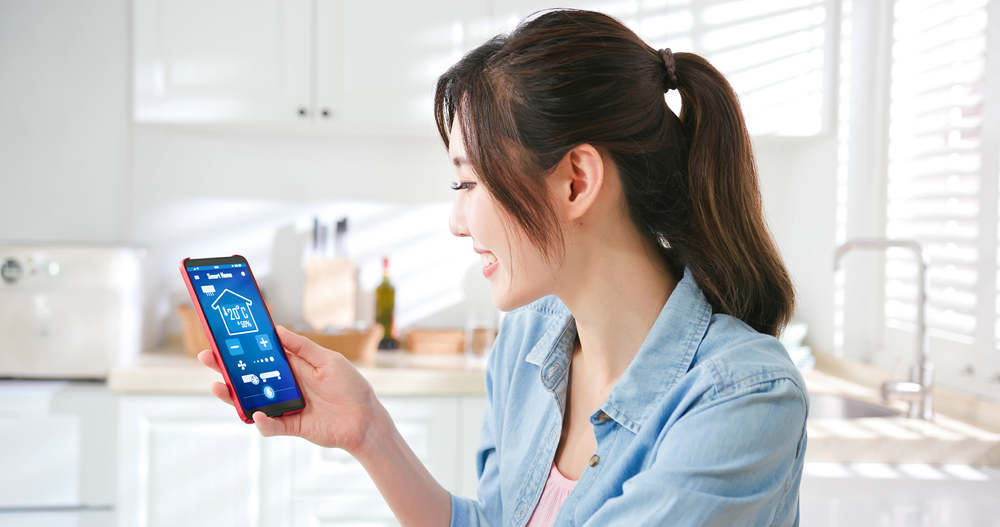 ญิงสาวใช้อุปกรณ์ IoT Smart Home ในบ้าน เพื่อเพิ่มความสะดวกสบายและความปลอดภัยให้มากขึ้น